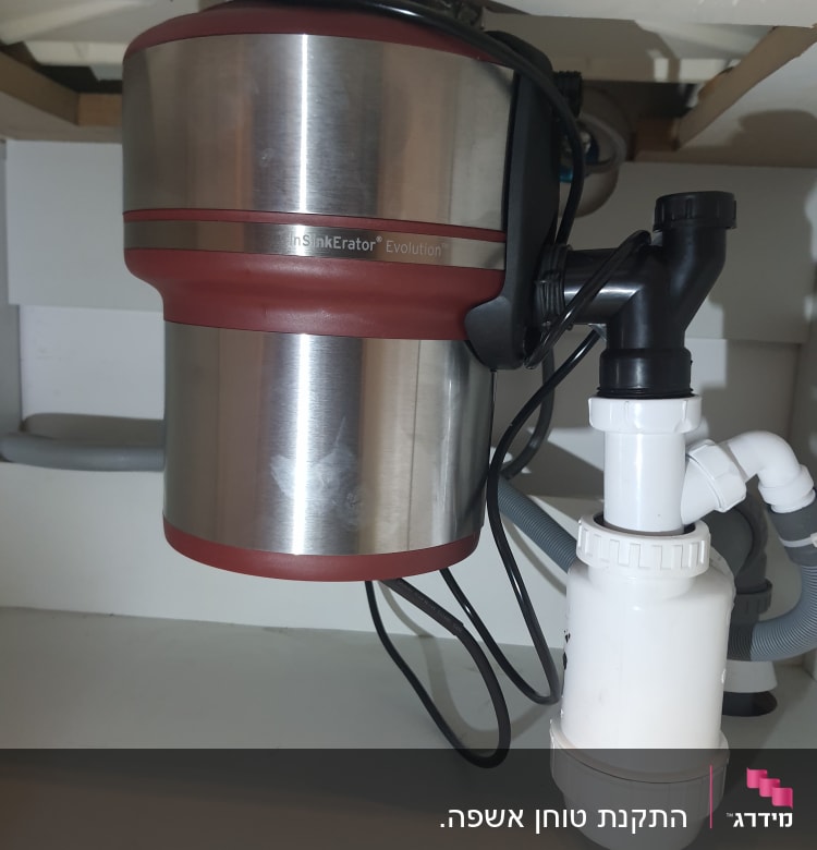 מכשיר טוחן אשפה מתחת לכיור עם צינורות חיבור